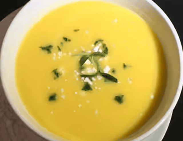 Yellow soup topped with herbs