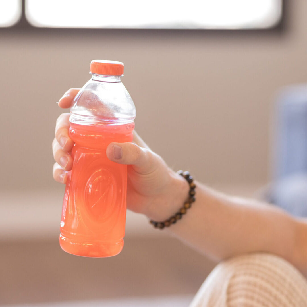 Hand holding orange sports drink bottle